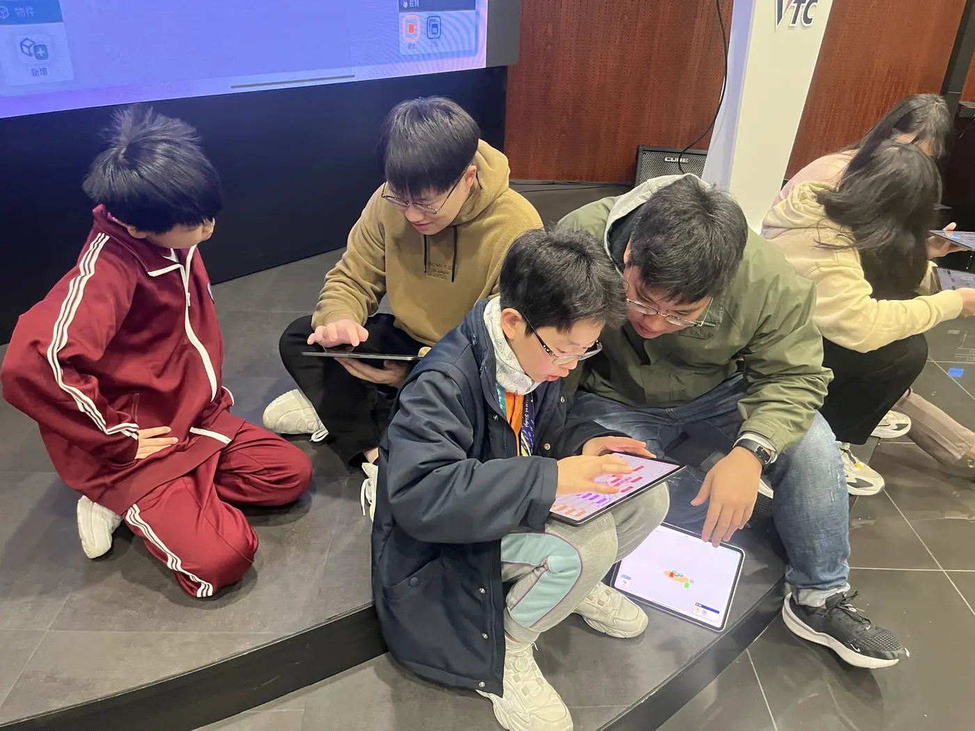 導師與學生圍坐地上,一起在 iPad 上創作